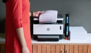 Người dùng đang xem xét các mẫu máy in gia đình trên bàn làm việc để lựa chọn thiết bị phù hợp nhu cầu.