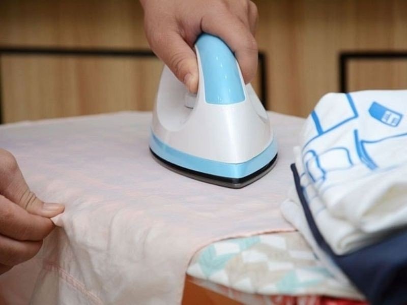 Dùng bàn là và giấy nến để làm nóng và loại bỏ hình in bị bong tróc trên áo
