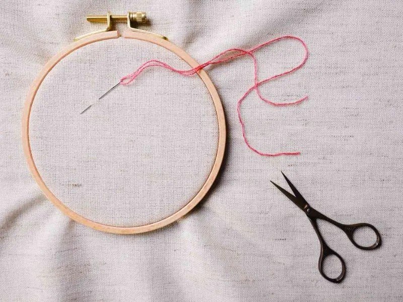 Một người đang chuẩn bị khung thêu đã có họa tiết để in lên áo, minh họa cho phương pháp in áo sử dụng khung thêu.