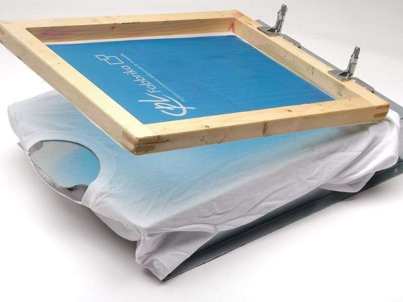 Cận cảnh quá trình phơi khung in lưới dưới ánh sáng để keo chụp bản đông cứng lại theo hình mẫu.