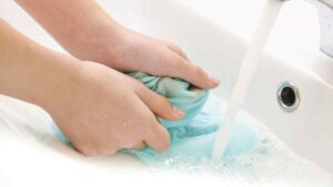 Người dùng đang chà nhẹ vết sơn trên áo bằng bông gòn
