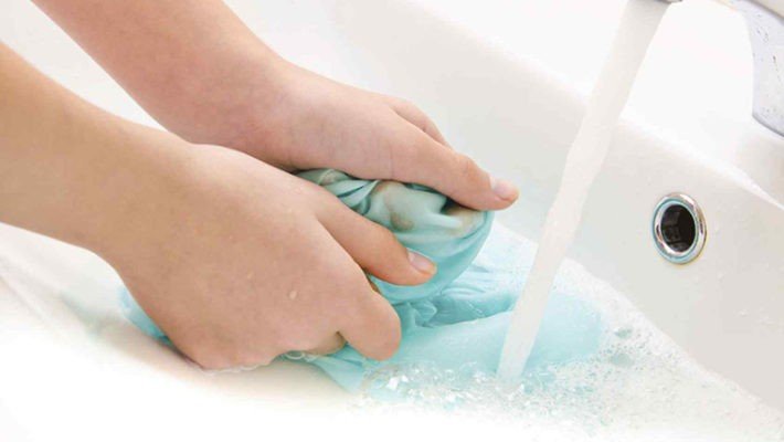 Người dùng đang chà nhẹ vết sơn trên áo bằng bông gòn