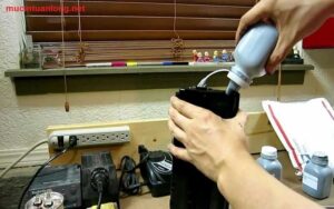 Kỹ thuật viên đang tiến hành nạp mực cho máy in văn phòng tại quận 3 một cách cẩn thận
