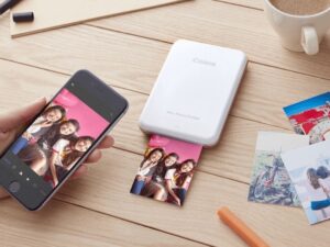 Người phụ nữ đang sử dụng máy in ảnh mini kết nối với điện thoại