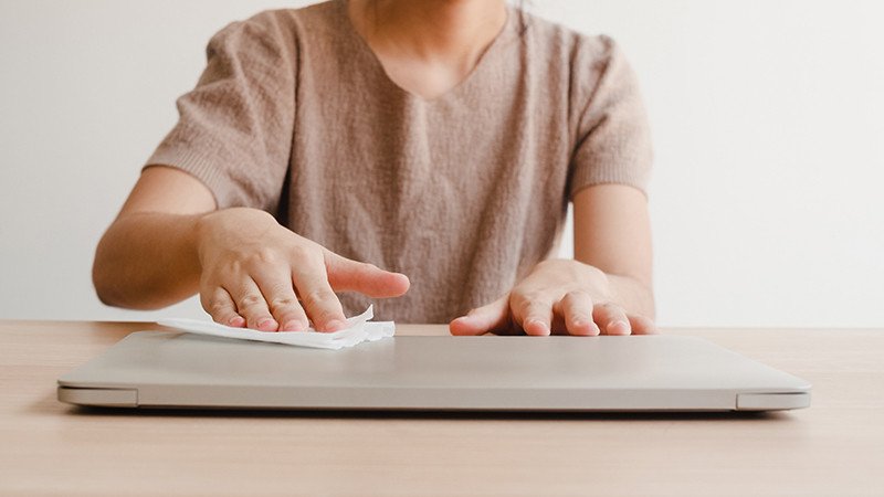 Người dùng đang lau sạch bề mặt vỏ máy khi vệ sinh máy tính laptop